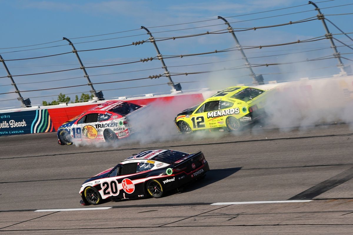 Sep 1, 2024; Darlington, South Carolina, USA; NASCAR Cup Series driver Christopher Bell (20) passes under the crashing cars of NASCAR Cup Series driver Martin Truex Jr. (19) and NASCAR Cup Series driver Ryan Blaney (12) during the Cook Out Southern 500 at Darlington Raceway. Mandatory Credit: Jasen Vinlove-Imagn Images