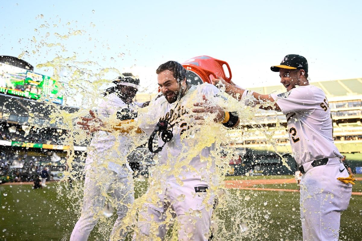 Sep 2, 2024; Oakland, California, USA; Oakland Athletics outfielder Lawrence Butler (left) and shortstop Max Schuemann (right) douse catcher Shea Langeliers (center) after his walk-off home run against the Seattle Mariners at Oakland-Alameda County Coliseum. Mandatory Credit: Eakin Howard-USA TODAY Sports