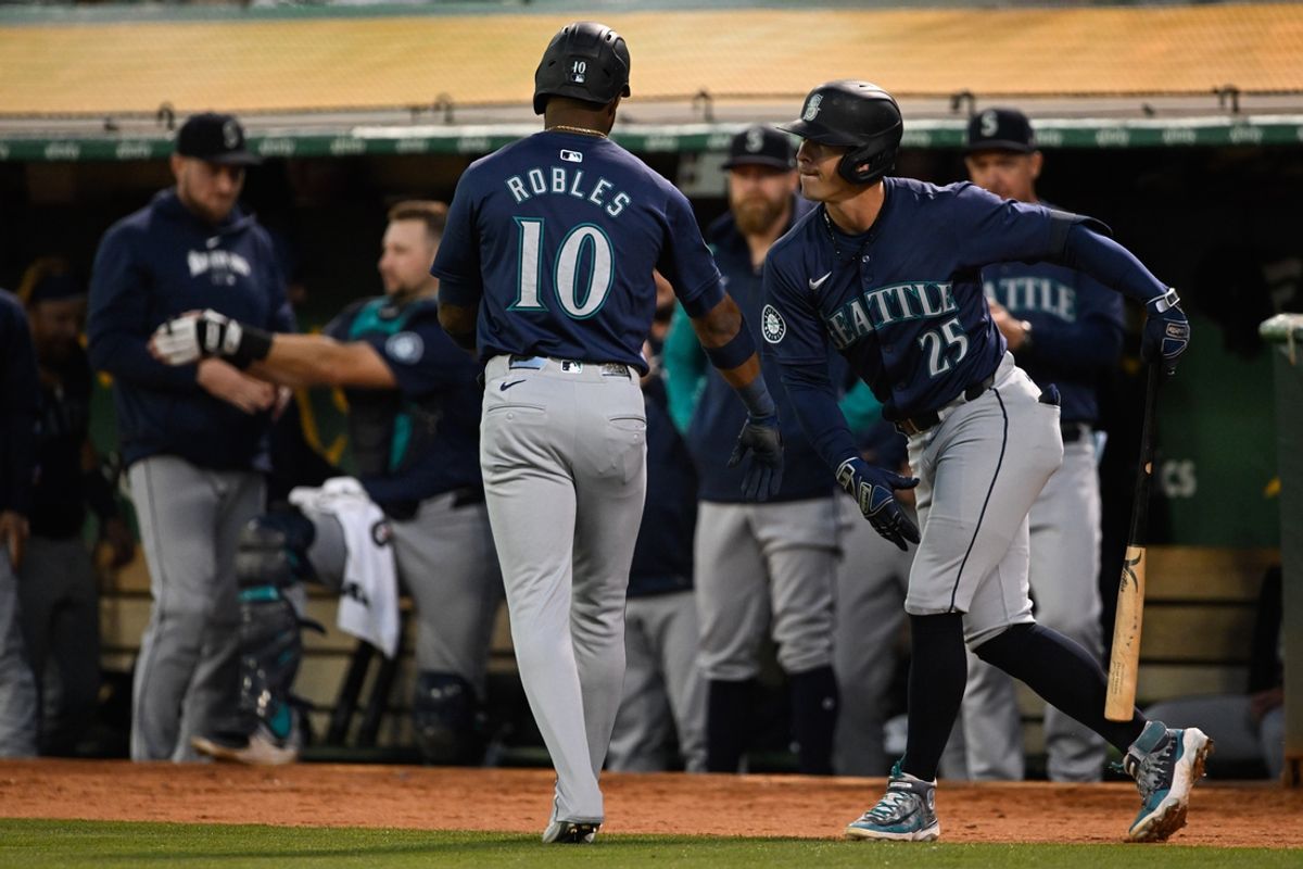 Sep 4, 2024; Oakland, California, USA; Seattle Mariners second baseman Dylan Moore (25) celebrates with outfielder Victor Robles (10) after his run against the Oakland Athletics in the fourth inning at Oakland-Alameda County Coliseum. Mandatory Credit: Eakin Howard-Imagn Images