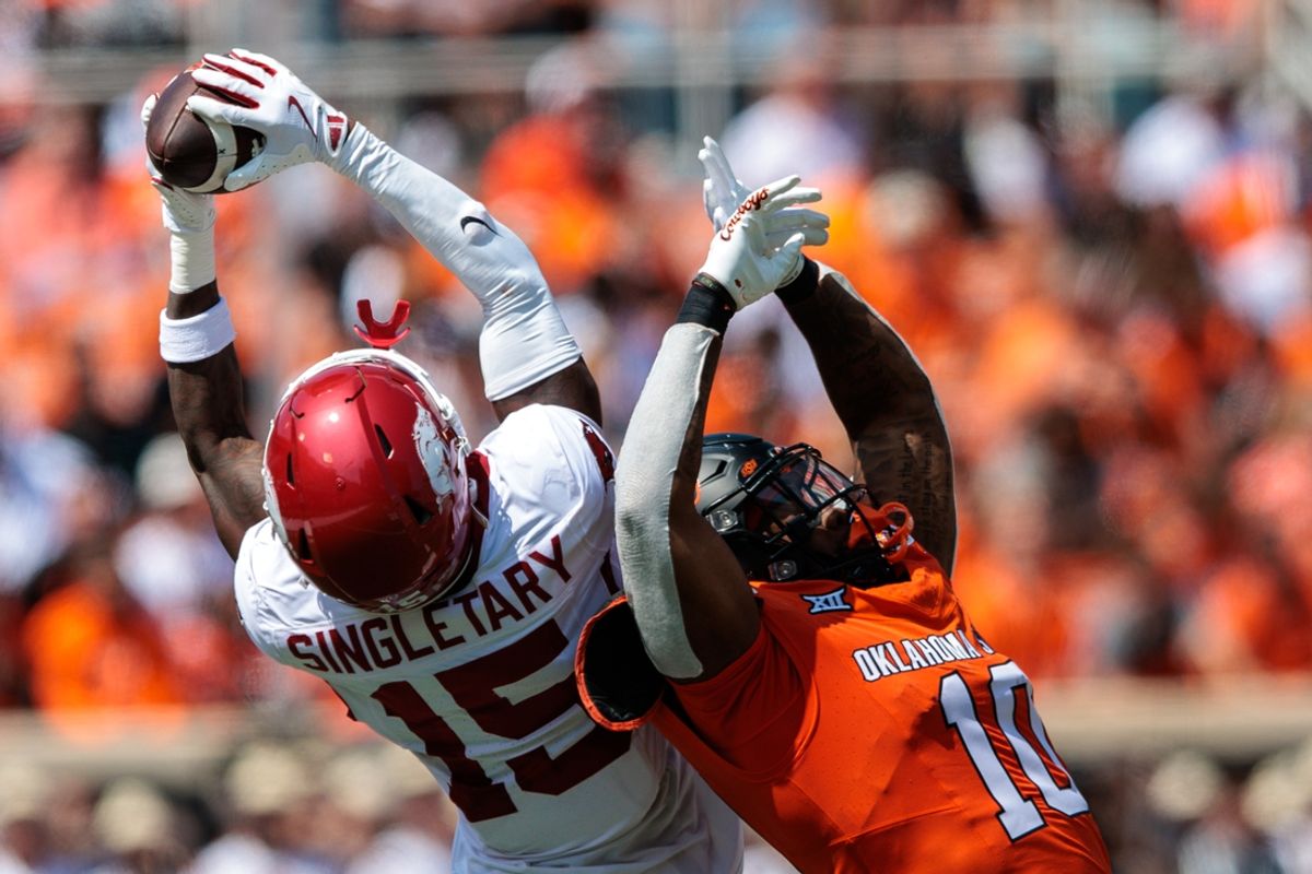 Sep 7, 2024; Stillwater, Oklahoma, USA; Arkansas Razorbacks defensive back Jaheim Singletary (15) makes an interception over Oklahoma State Cowboys wide receiver Rashod Owens (10) during the second quarter at Boone Pickens Stadium. Mandatory Credit: William Purnell-Imagn Images