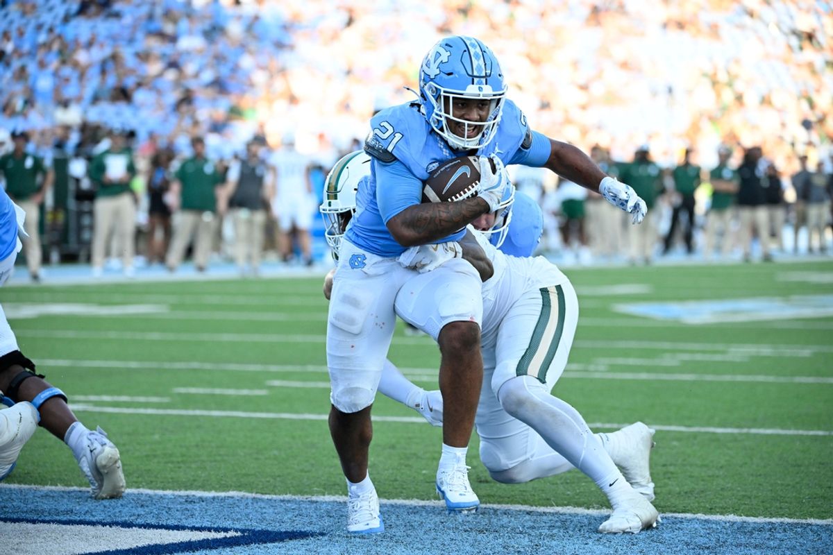Sep 7, 2024; Chapel Hill, North Carolina, USA; North Carolina Tar Heels running back Davion Gause (21) scores a touchdown as Charlotte 49ers defensive lineman Chantz Williams (14) defends in the fourth quarter at Kenan Memorial Stadium. Mandatory Credit: Bob Donnan-Imagn Images