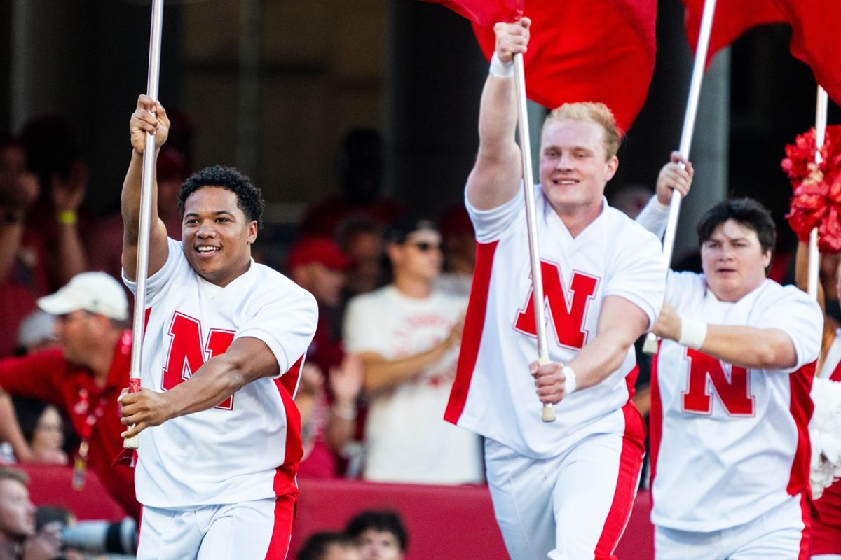 Sep 7, 2024; Lincoln, Nebraska, USA; Nebraska Cornhuskers cheerleaders carry flags across the field after a touchdown against the Colorado Buffaloes during the first quarter at Memorial Stadium. Mandatory Credit: Dylan Widger-Imagn Images