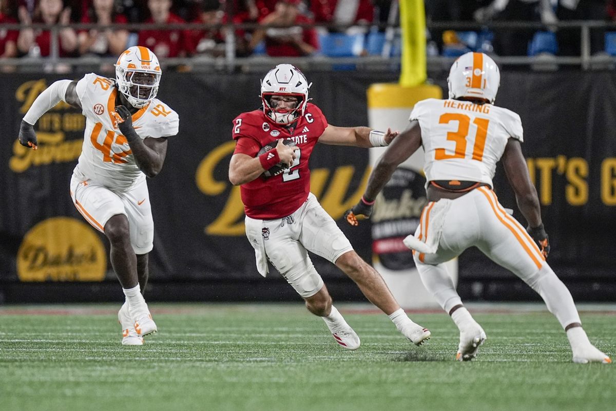 Sep 7, 2024; Charlotte, North Carolina, USA; North Carolina State Wolfpack quarterback Grayson McCall (2) runs with the football as Tennessee Volunteers defensive lineman Tyre West (42) and defensive lineman Caleb Herring (31) defend during the second half at the Dukes Mayo Classic at Bank of America Stadium. Mandatory Credit: Jim Dedmon-Imagn Images