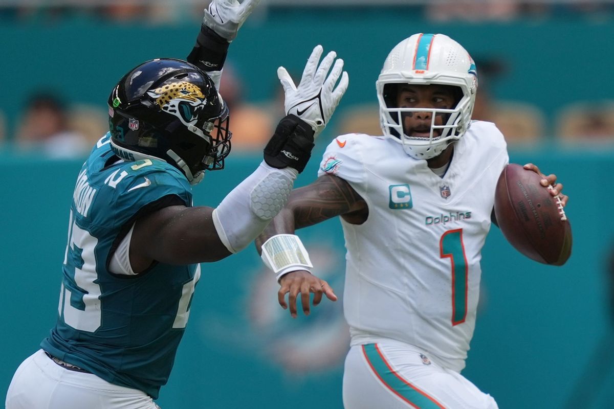 Miami Dolphins quarterback Tua Tagovailoa (1) rolls out to pass as linebacker Foyesade Oluokun (23) follows on the play at Hard Rock Stadium.