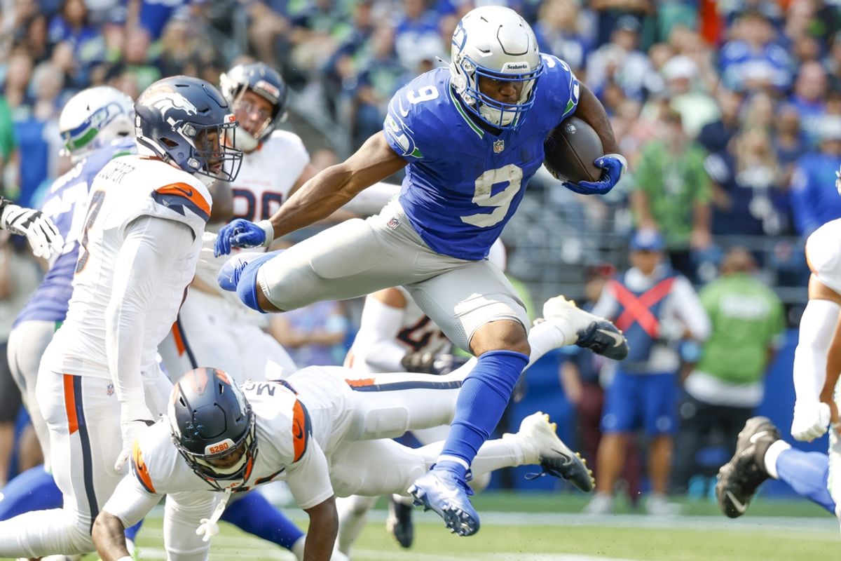 Sep 8, 2024; Seattle, Washington, USA; Seattle Seahawks running back Kenneth Walker III (9) jumps over a tackle attempt by Denver Broncos cornerback JaQuan McMillian (29) during the second quarter at Lumen Field. Mandatory Credit: Joe Nicholson-Imagn Images