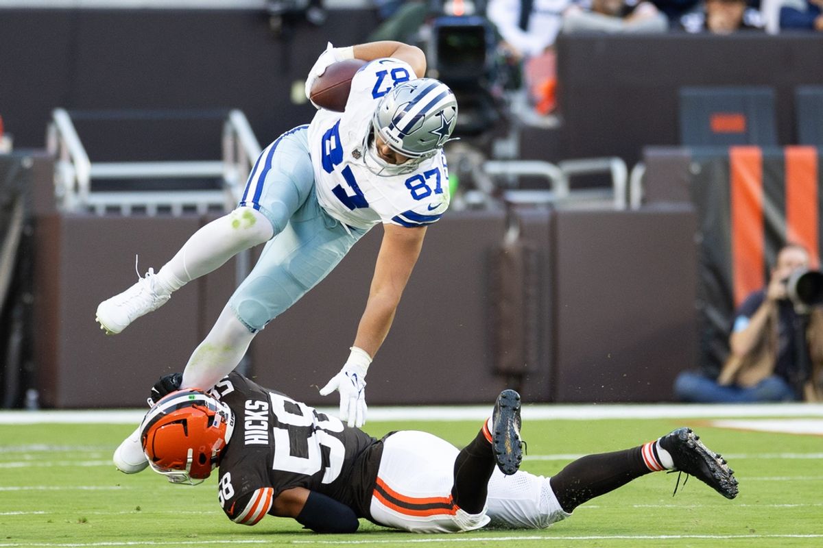 Sep 8, 2024; Cleveland, Ohio, USA; Dallas Cowboys tight end Jake Ferguson (87) falls over Cleveland Browns linebacker Jordan Hicks (58) as he is tackled around his ankle during the third quarter at Huntington Bank Field. Mandatory Credit: Scott Galvin-Imagn Images
