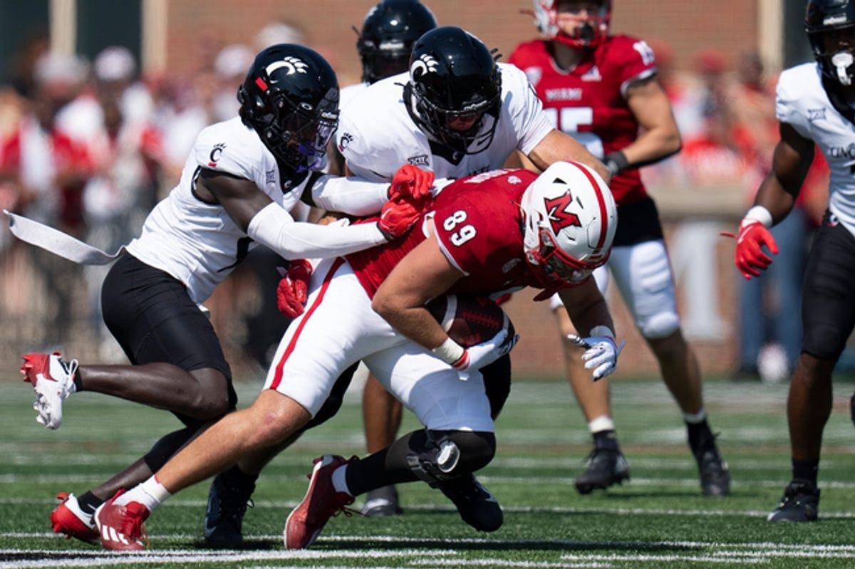 Miami Redhawks tight end Jack Coldiron (89) is tackled by Cincinnati Bearcats linebacker Jack Dingle (49) and Cincinnati Bearcats defensive back Jiquan Sanks (9) tackles in the first quarter of the College Football game at Yager Stadium in Cincinnati on Saturday, Sept. 14, 2024.