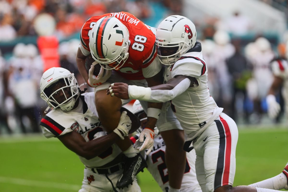 Sep 14, 2024; Miami Gardens, Florida, USA; Miami Hurricanes tight end Riley Williams (88) runs with the football against Ball State Cardinals linebackers Keionte Newson (9) and Caden Johnson (6) during the first quarter at Hard Rock Stadium. Mandatory Credit: Sam Navarro-Imagn Images