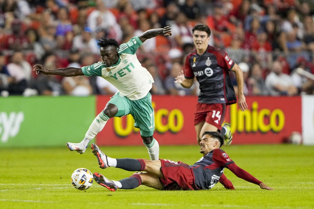 Sep 14, 2024; Toronto, Ontario, CAN; Austin FC midfielder Emiliano Rigoni (7) avoids a slide tackle by Toronto FC defender Raoul Petretta (28) during the first half at BMO Field. Mandatory Credit: Kevin Sousa-Imagn Images