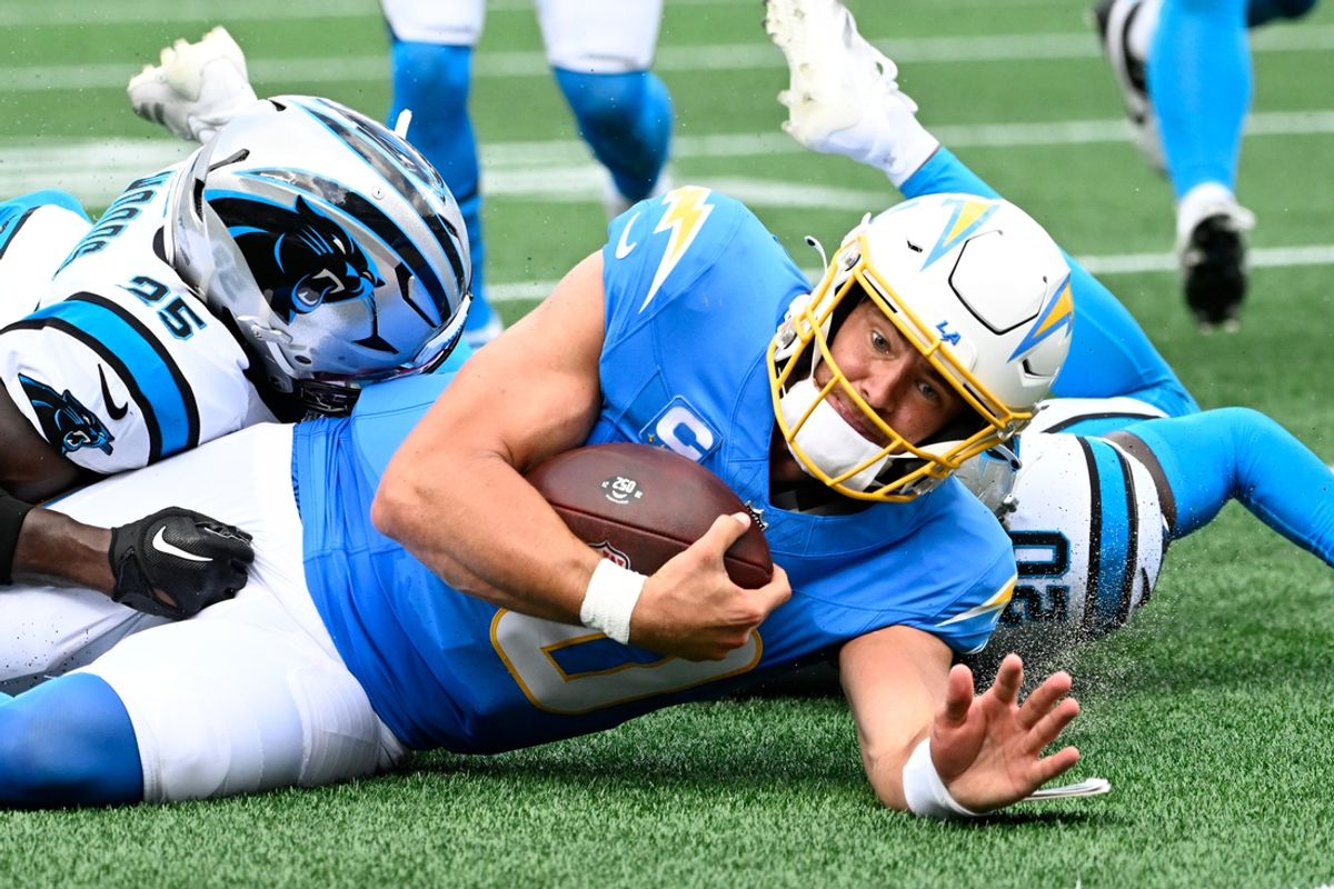 Sep 15, 2024; Charlotte, North Carolina, USA;  Los Angeles Chargers quarterback Justin Herbert (10) is tackled by Carolina Panthers safety Xavier Woods (25) and safety Jordan Fuller (20) in the second quarter at Bank of America Stadium. Mandatory Credit: Bob Donnan-Imagn Images