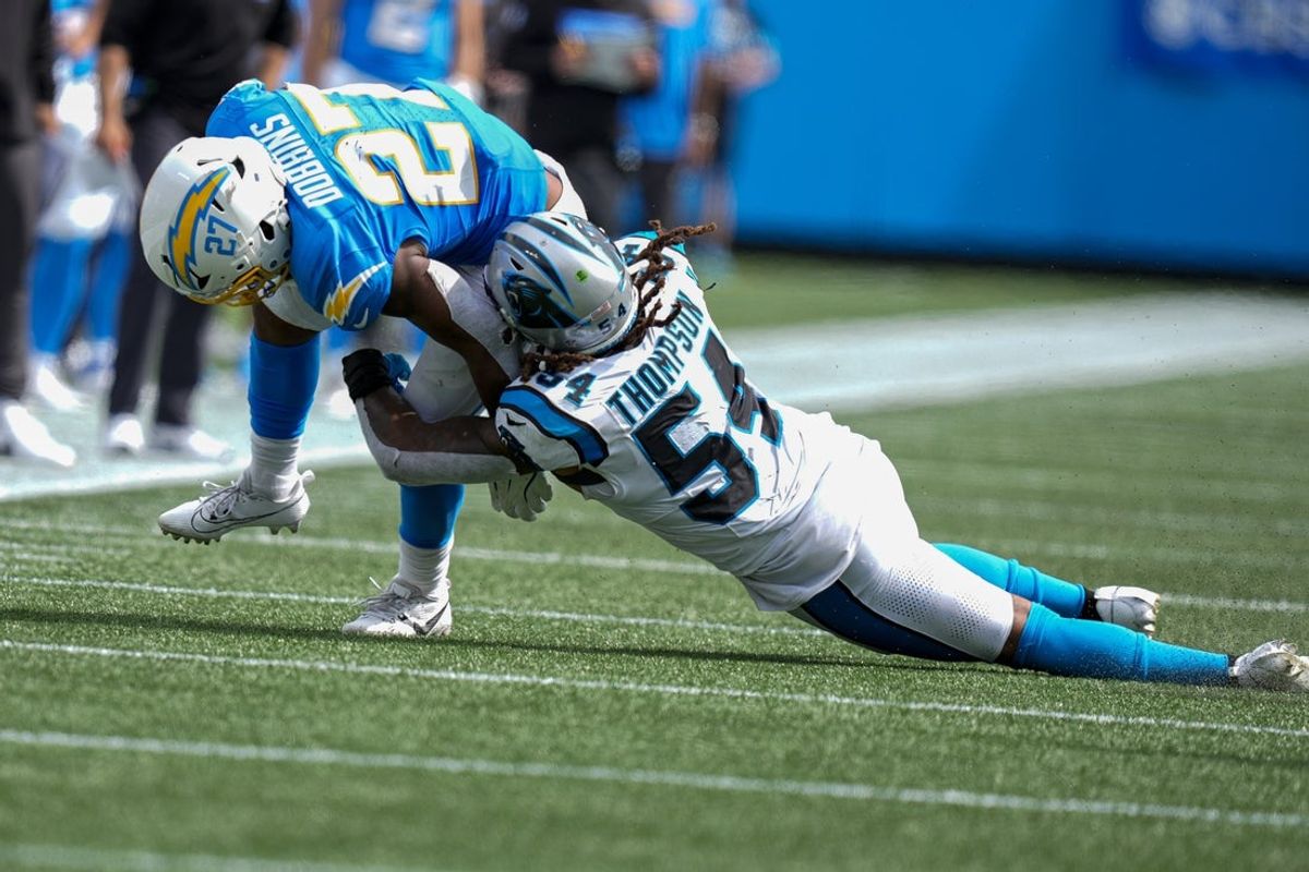 Sep 15, 2024; Charlotte, North Carolina, USA;  Los Angeles Chargers running back J.K. Dobbins (27) is tackled by Carolina Panthers linebacker Shaq Thompson (54) during the second half at Bank of America Stadium. Mandatory Credit: Jim Dedmon-Imagn Images