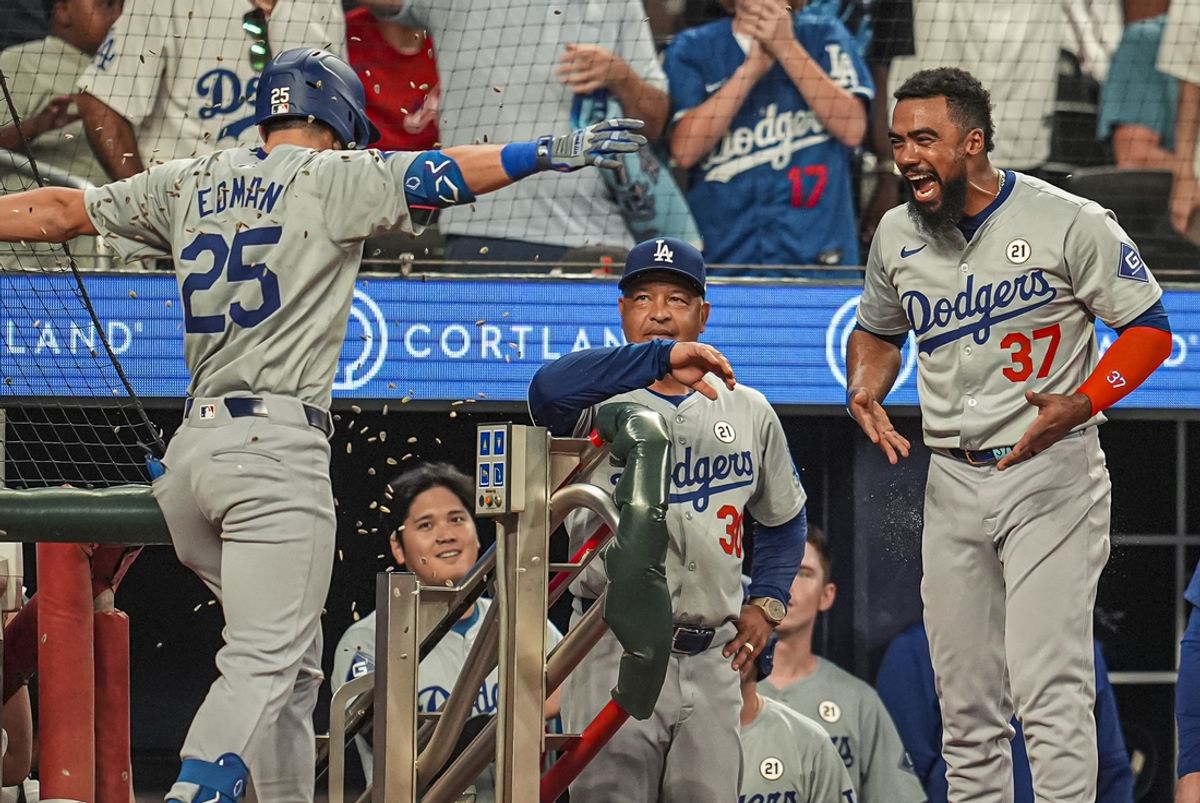 Sep 15, 2024; Cumberland, Georgia, USA; Los Angeles Dodgers shortstop Tommy Edman (25) is hit with seeds by left fielder Teoscar Hernandez (37) after hitting a home run against the Atlanta Braves during the ninth inning at Truist Park. Mandatory Credit: Dale Zanine-Imagn Images