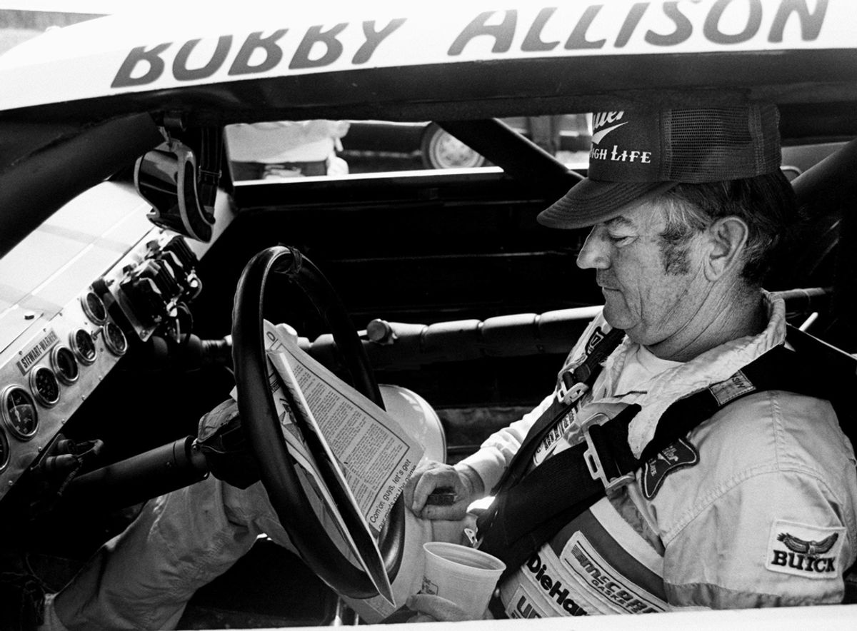 The defending Winston Cup points champion Bobby Allison checks out the newspaper during qualifying trials for the Nashville Pepsi 420 NASCAR Grand National race at Nashville International Raceway on July 13, 1984