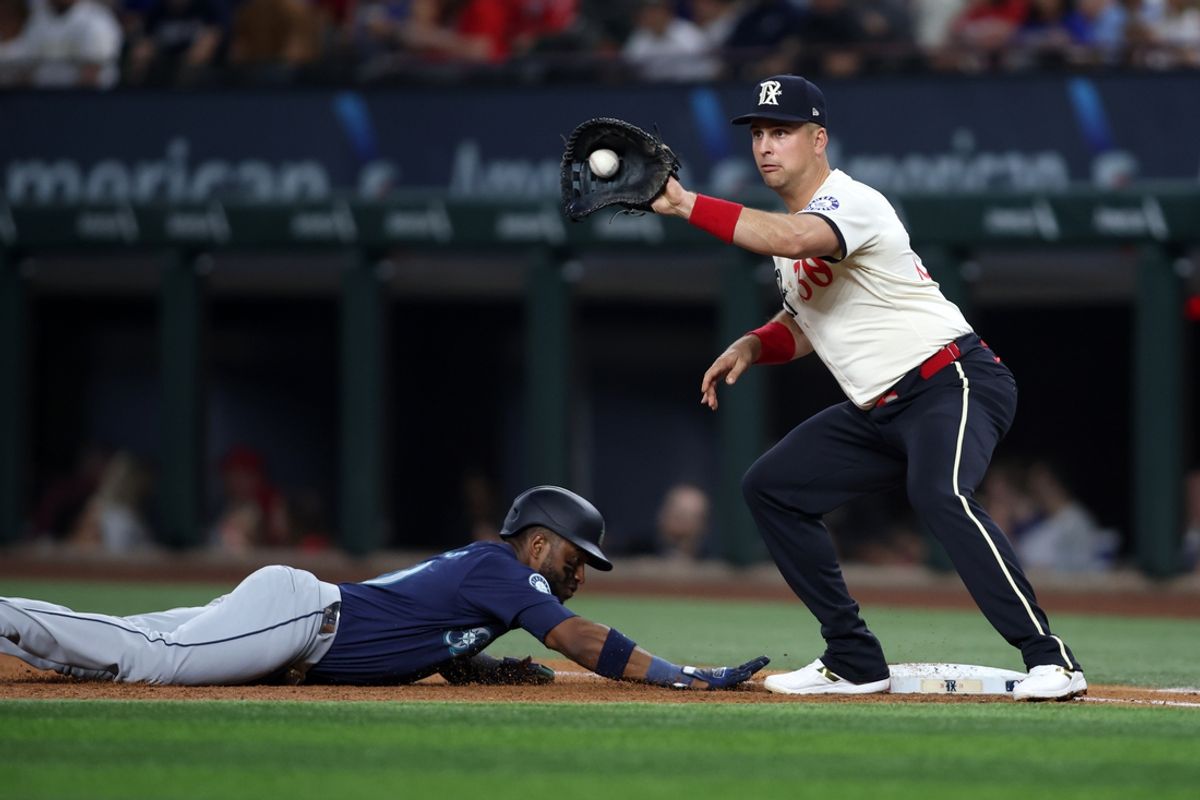 Sep 20, 2024; Arlington, Texas, USA; Texas Rangers first baseman Nathaniel Lowe (30) catches a throw as Seattle Mariners right fielder Victor Robles (10) dives back to first base in the third inning at Globe Life Field. Mandatory Credit: Tim Heitman-Imagn Images