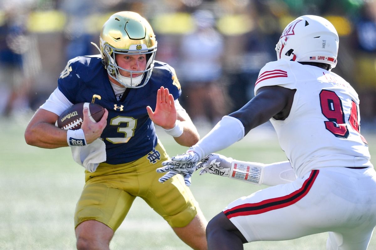 Sep 21, 2024; South Bend, Indiana, USA; Notre Dame Fighting Irish quarterback Riley Leonard (13) runs the ball as Miami Redhawks defensive end Josh Lukusa (94) defends in the second quarter at Notre Dame Stadium. Mandatory Credit: Matt Cashore-Imagn Images