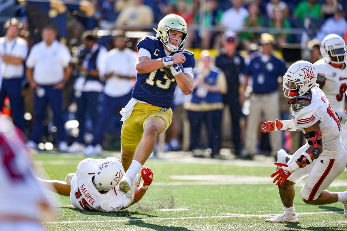 Sep 21, 2024; South Bend, Indiana, USA; Notre Dame Fighting Irish quarterback Riley Leonard (13) runs for a touchdown as Miami Redhawks linebacker Matt Salopek (15) defends in the second quarter at Notre Dame Stadium. Mandatory Credit: Matt Cashore-Imagn Images