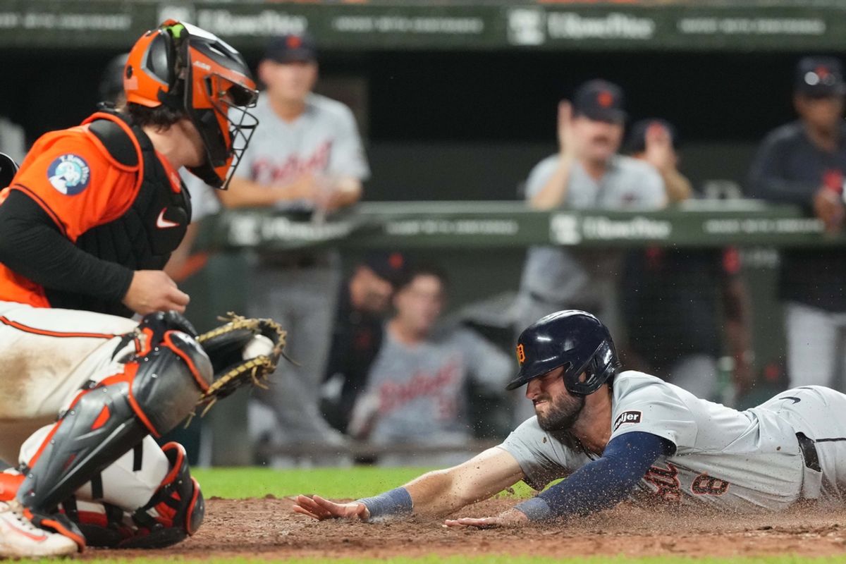 Sep 21, 2024; Baltimore, Maryland, USA; Detroit Tigers runner Matt Vierling (8) slides in with the game winning run in the tenth inning ahead of a tag by Baltimore Orioles catcher Adley Rutschman (35) at Oriole Park at Camden Yards. Mandatory Credit: Mitch Stringer-Imagn Images