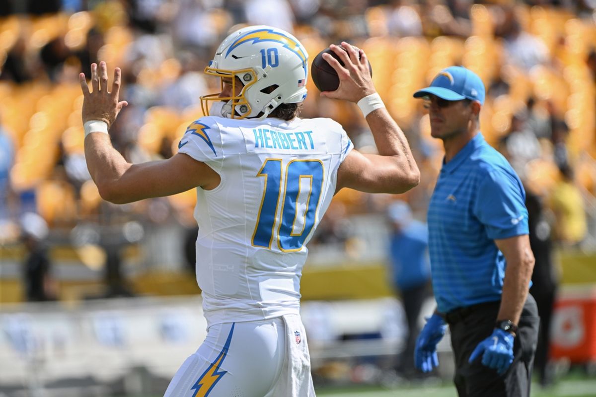 Sep 22, 2024; Pittsburgh, Pennsylvania, USA; Los Angeles Chargers quarterback Justin Herbert (10) works out as head coach Jim Harbaugh looks on before a game against the Pittsburgh Steelers at Acrisure Stadium. Mandatory Credit: Barry Reeger-Imagn Images