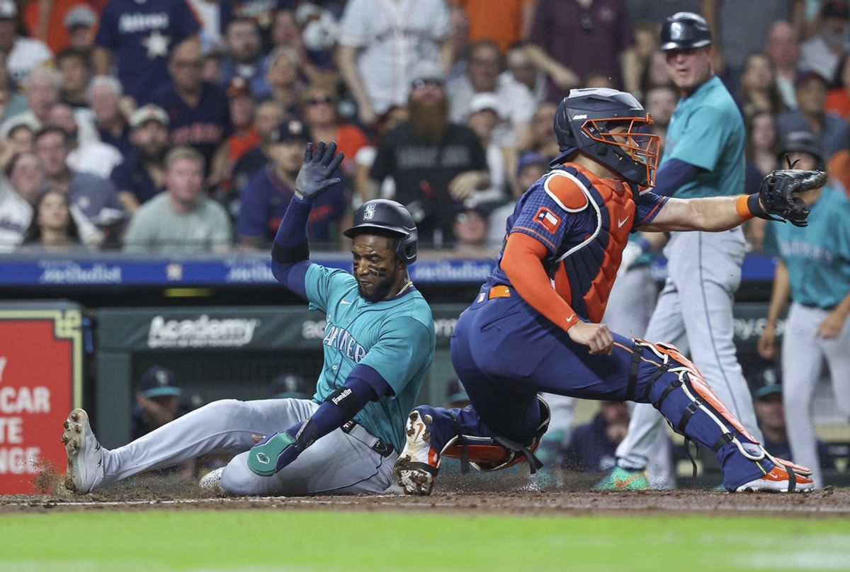 Sep 23, 2024; Houston, Texas, USA; Seattle Mariners right fielder Victor Robles (10) slides safely past Houston Astros catcher Yainer Diaz (21) to score a run during the third inning at Minute Maid Park. Mandatory Credit: Troy Taormina-Imagn Images