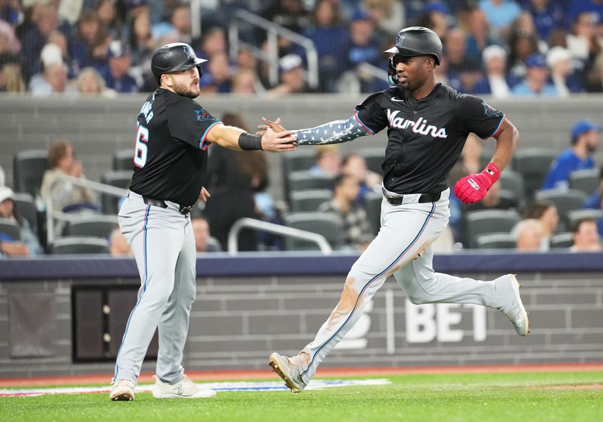 Sep 27, 2024; Toronto, Ontario, CAN; Miami Marlins right fielder Jesus Sanchez (12) scores a run and celebrates with left fielder Griffin Conine (56) against the Toronto Blue Jays during the fourth inning at Rogers Centre. Mandatory Credit: Nick Turchiaro-Imagn Images