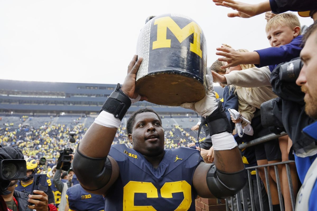 Sep 28, 2024; Ann Arbor, Michigan, USA;  Michigan Wolverines offensive lineman Raheem Anderson (62) lifts up the Little Brown Jug after defeating the Minnesota Golden Gophers at Michigan Stadium. Mandatory Credit: Rick Osentoski-Imagn Images