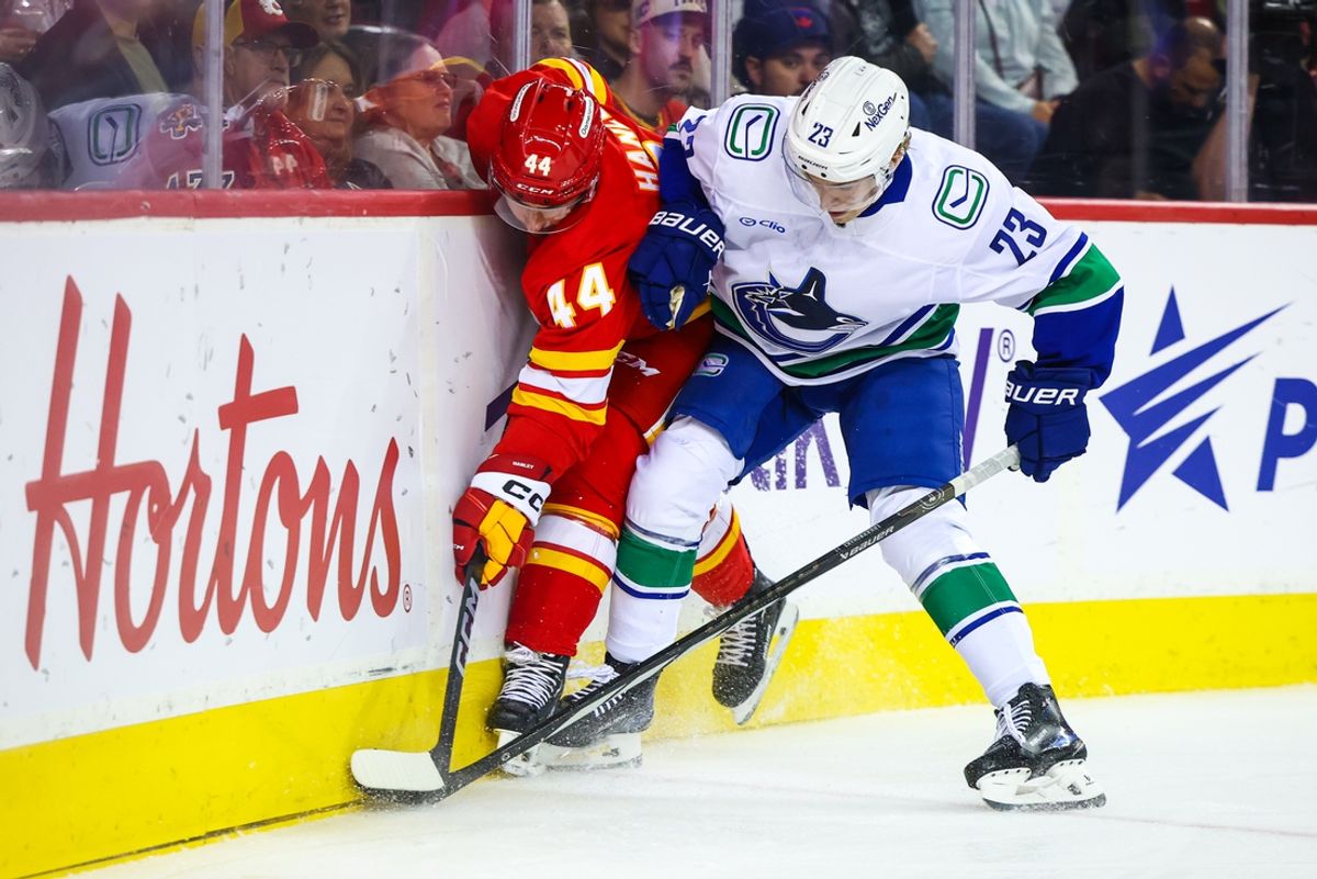 Sep 28, 2024; Calgary, Alberta, CAN; Calgary Flames defenseman Joel Hanley (44) and Vancouver Canucks right wing Jonathan Lekkerimaki (23) battles for the puck during the first period at Scotiabank Saddledome. Mandatory Credit: Sergei Belski-Imagn Images