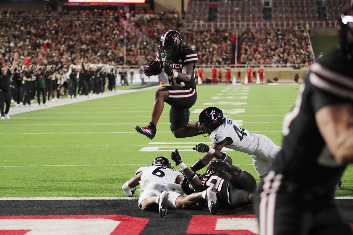 Sep 28, 2024; Lubbock, Texas, USA;  Texas Tech Red Raiders running back Tahj Brooks (28) hurdles Cincinnati Bearcats defensive safety Trevon Gola-Callard (6) for a touchdown in the first half at Jones AT&T Stadium and Cody Campbell Field. Mandatory Credit: Michael C. Johnson-Imagn Images