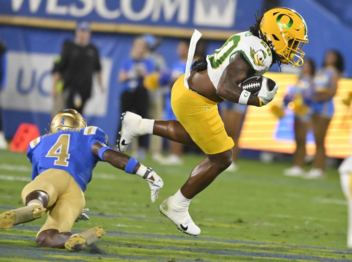 Sep 28, 2024; Pasadena, California, USA; Oregon Ducks running back Jordan James (20) leaps over UCLA Bruins defensive back Bryan Addison (4) during the first quarter at Rose Bowl. Mandatory Credit: Robert Hanashiro-Imagn Images