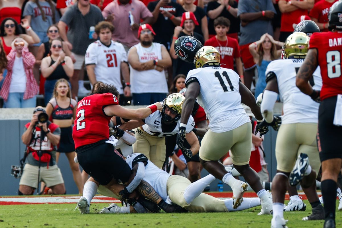Oct 5, 2024; Raleigh, North Carolina, USA;  North Carolina State Wolfpack quarterback Grayson McCall (2) gets tackled without his helmet by Wake Forest Demon Deacons linebacker Quincy Bryant (9) and linebacker Dylan Hazen (24) during the first half of the game at Carter-Finley Stadium. Mandatory Credit: Jaylynn Nash-Imagn Images