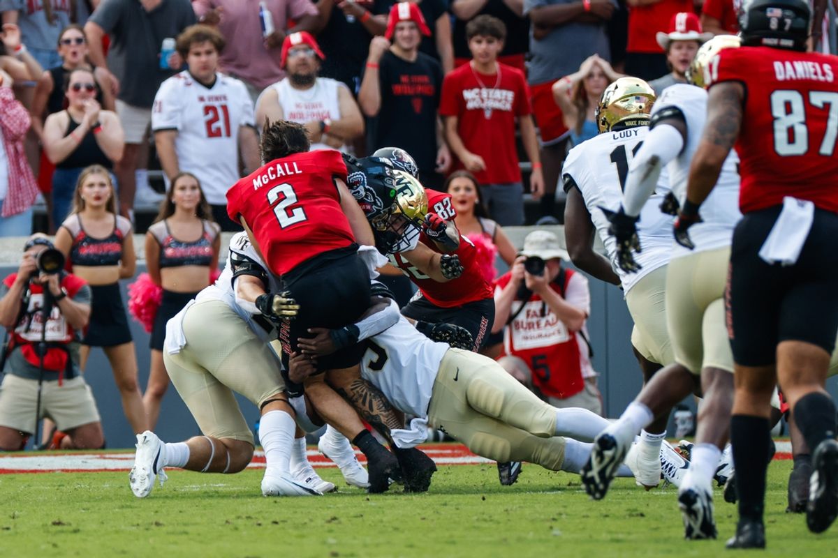 Oct 5, 2024; Raleigh, North Carolina, USA;  North Carolina State Wolfpack quarterback Grayson McCall (2) gets tackled without his helmet by Wake Forest Demon Deacons linebacker Quincy Bryant (9) and linebacker Dylan Hazen (24) during the first half of the game at Carter-Finley Stadium. Mandatory Credit: Jaylynn Nash-Imagn Images