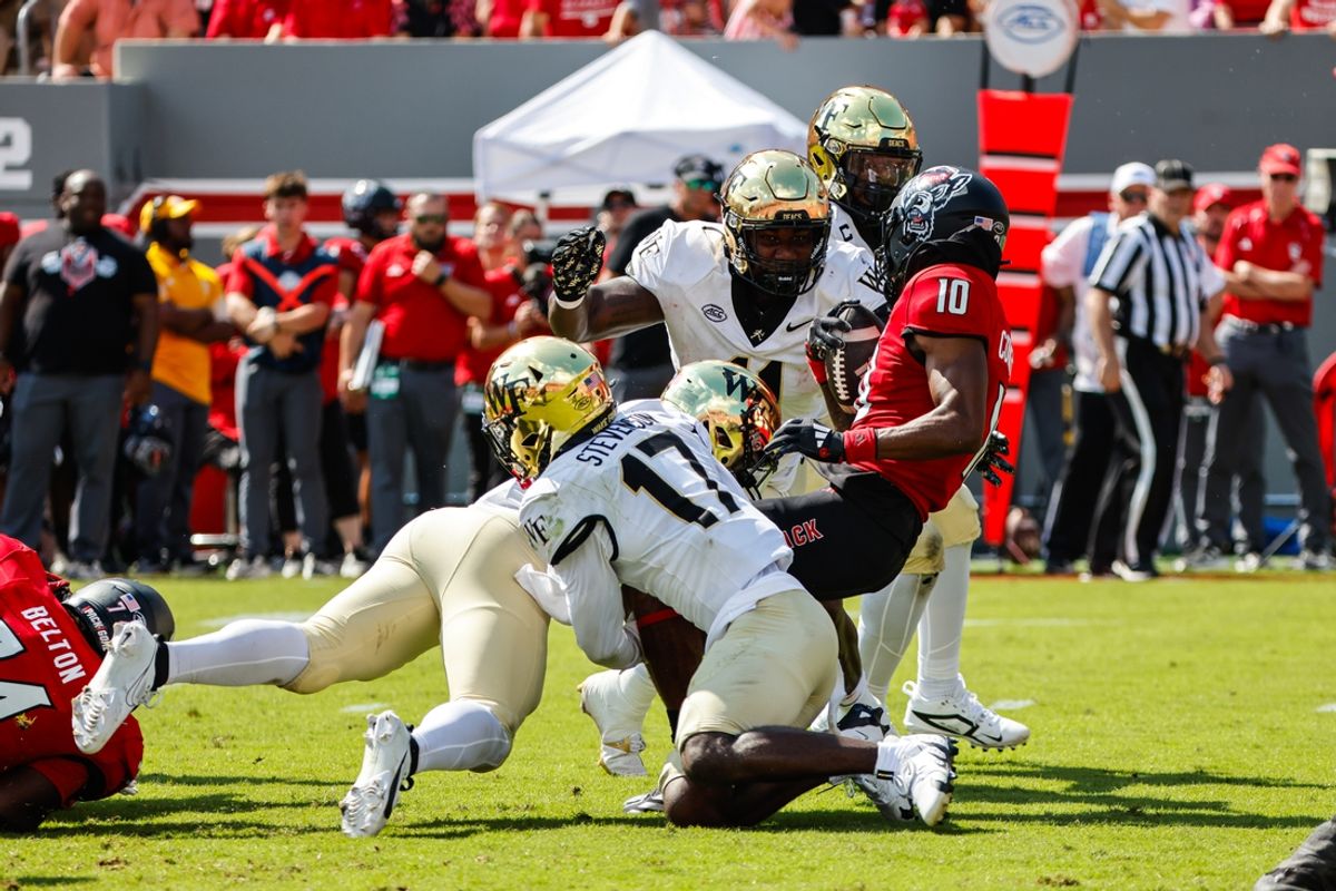 Oct 5, 2024; Raleigh, North Carolina, USA; Wake Forest Demon Deacons defensive lineman Justin Cody (11) and players tackle North Carolina State Wolfpack wide receiver Kevin Concepcion (10) during the first half of the game against at Carter-Finley Stadium. Mandatory Credit: Jaylynn Nash-Imagn Images