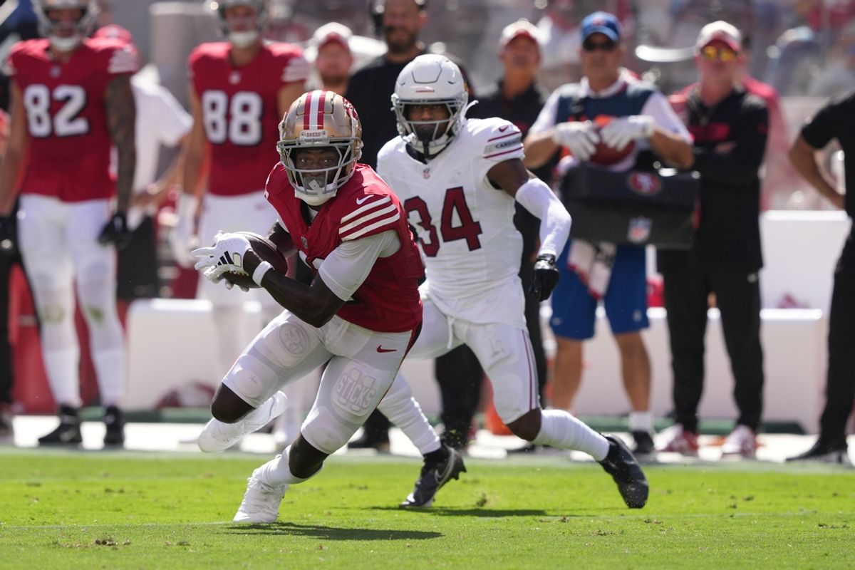Oct 6, 2024; Santa Clara, California, USA; San Francisco 49ers wide receiver Brandon Aiyuk (left) runs after a catch against Arizona Cardinals safety Jalen Thompson (34) during the second quarter at Levi's Stadium. Mandatory Credit: Darren Yamashita-Imagn Images