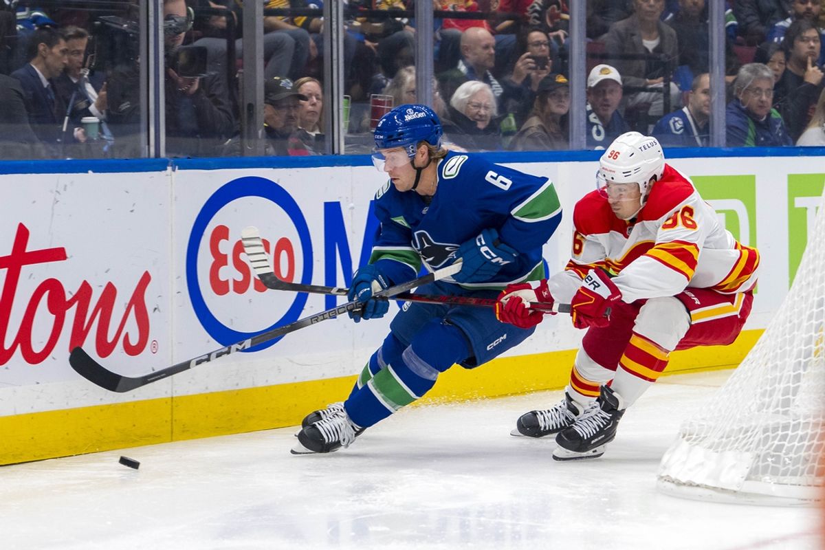 Oct 9, 2024; Vancouver, British Columbia, CAN; Calgary Flames forward Andrei Kuzmenko (96) stick checks Vancouver Canucks forward Brock Boeser (6) during the first period at Rogers Arena. Mandatory Credit: Bob Frid-Imagn Images