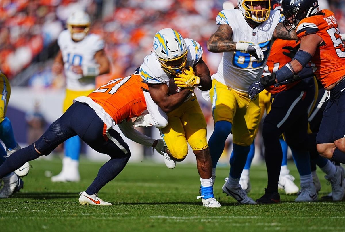 Oct 13, 2024; Denver, Colorado, USA; Denver Broncos cornerback Riley Moss (21) reaches for Los Angeles Chargers running back J.K. Dobbins (27) in the second quarter at Empower Field at Mile High. Mandatory Credit: Ron Chenoy-Imagn Images