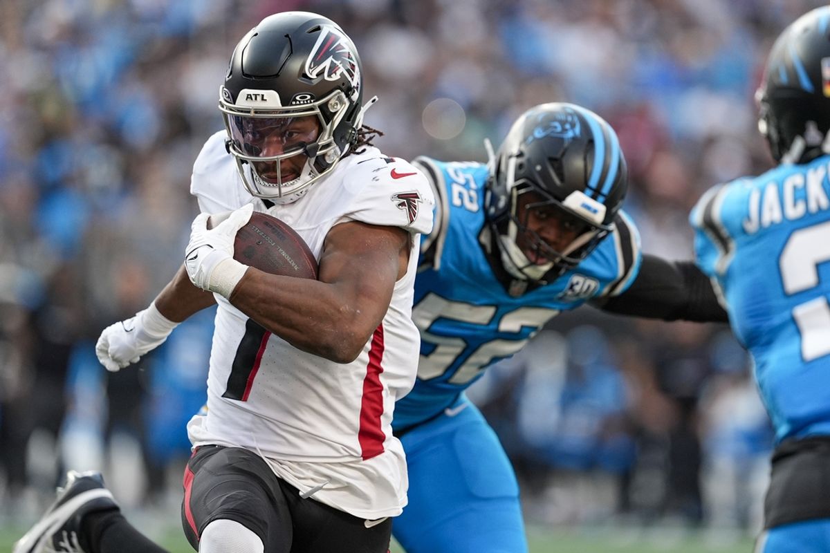 Oct 13, 2024; Charlotte, North Carolina, USA; Atlanta Falcons running back Bijan Robinson (7) eludes Carolina Panthers linebacker DJ Johnson (52) in the red zone during the second quarter at Bank of America Stadium. Mandatory Credit: Jim Dedmon-Imagn Images