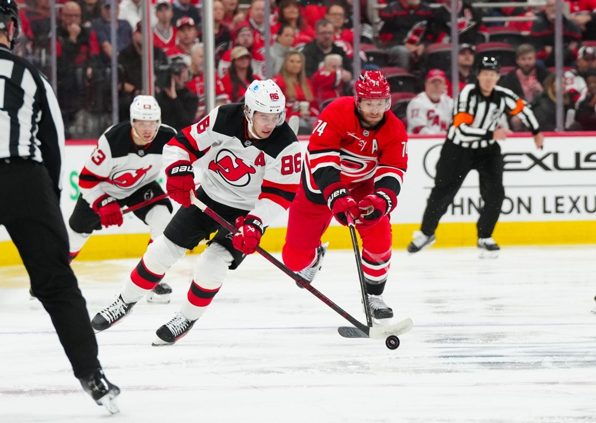 Oct 15, 2024; Raleigh, North Carolina, USA;  New Jersey Devils center Jack Hughes (86) skates with the puck past Carolina Hurricanes defenseman Jaccob Slavin (74) during the second period at PNC Arena. Mandatory Credit: James Guillory-Imagn Images