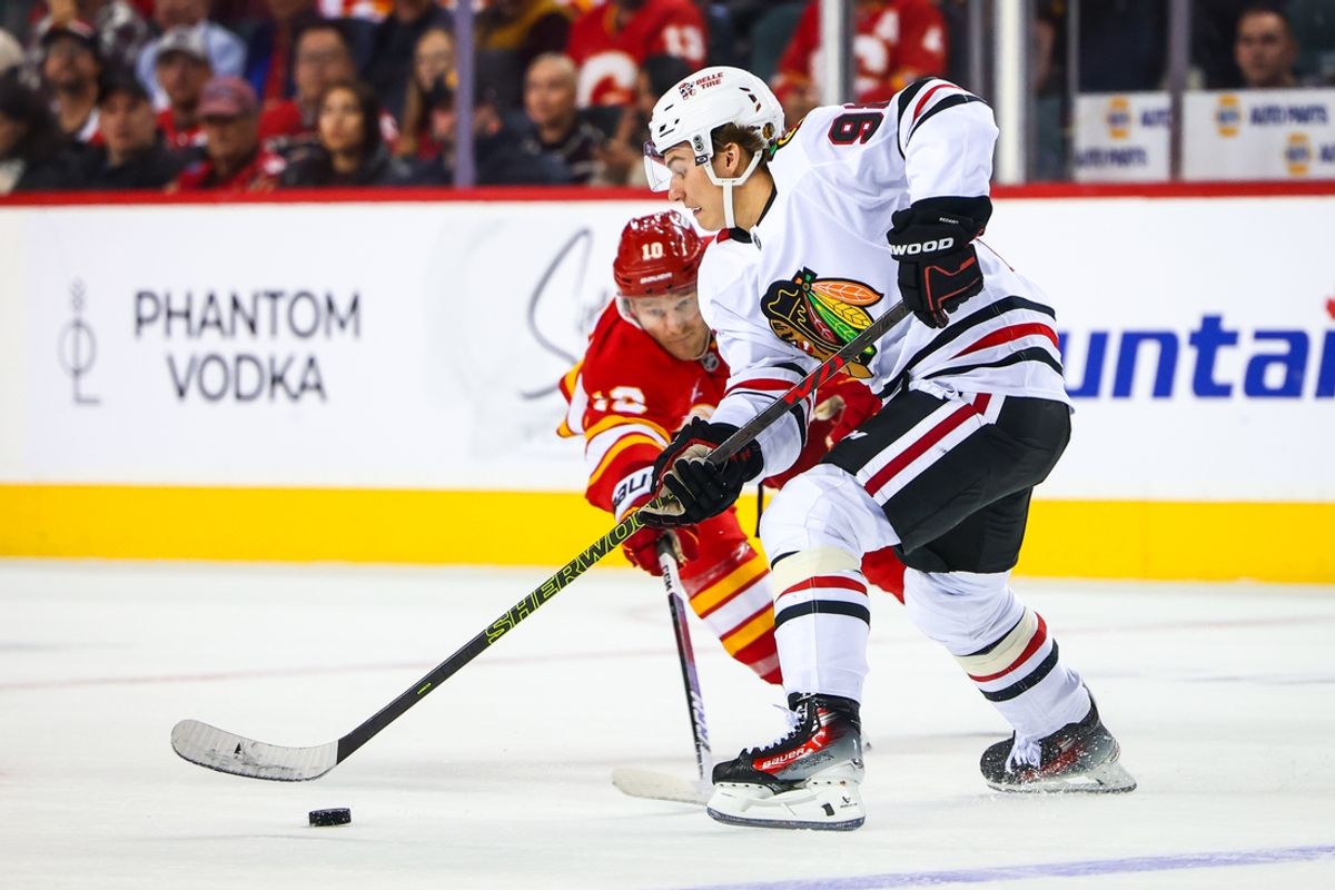 Oct 15, 2024; Calgary, Alberta, CAN; Chicago Blackhawks center Connor Bedard (98) controls the puck against Calgary Flames center Jonathan Huberdeau (10) during the third period at Scotiabank Saddledome. Mandatory Credit: Sergei Belski-Imagn Images