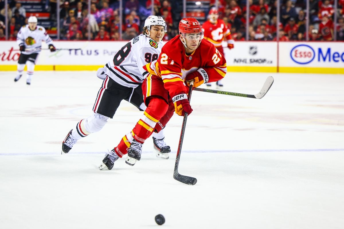 Oct 15, 2024; Calgary, Alberta, CAN; Calgary Flames right wing Matt Coronato (27) controls the puck against Chicago Blackhawks center Connor Bedard (98) during the third period at Scotiabank Saddledome. Mandatory Credit: Sergei Belski-Imagn Images