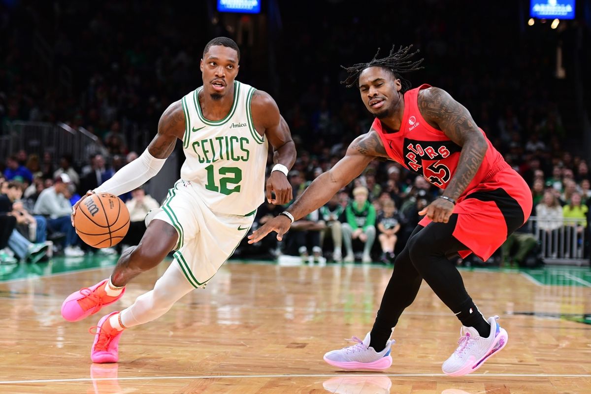 Oct 13, 2024; Boston, Massachusetts, USA;  Boston Celtics guard Lonnie Walker IV (12) controls the ball while Toronto Raptors guard Davion Mitchell (45) defends during the first half at TD Garden. Mandatory Credit: Bob DeChiara-Imagn Images