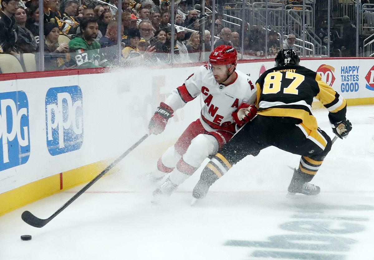 Oct 18, 2024; Pittsburgh, Pennsylvania, USA;  Carolina Hurricanes defenseman Jaccob Slavin (74) reaches for the puck against Pittsburgh Penguins center Sidney Crosby (87) during the first period at PPG Paints Arena. Mandatory Credit: Charles LeClaire-Imagn Images