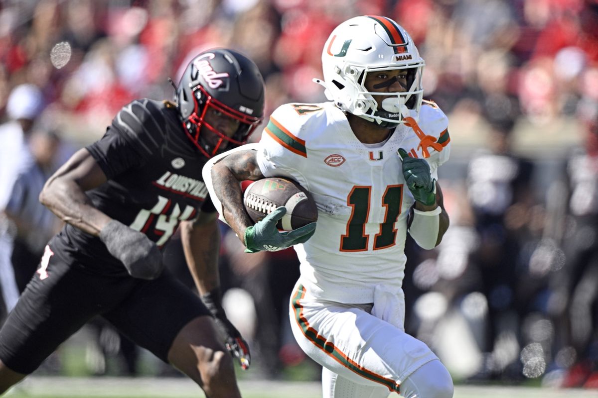 Oct 19, 2024; Louisville, Kentucky, USA; Miami Hurricanes wide receiver Samuel Brown (11) runs the ball against Louisville Cardinals defensive back Corey Thornton (14) during the first half at L&N Federal Credit Union Stadium. Mandatory Credit: Jamie Rhodes-Imagn Images