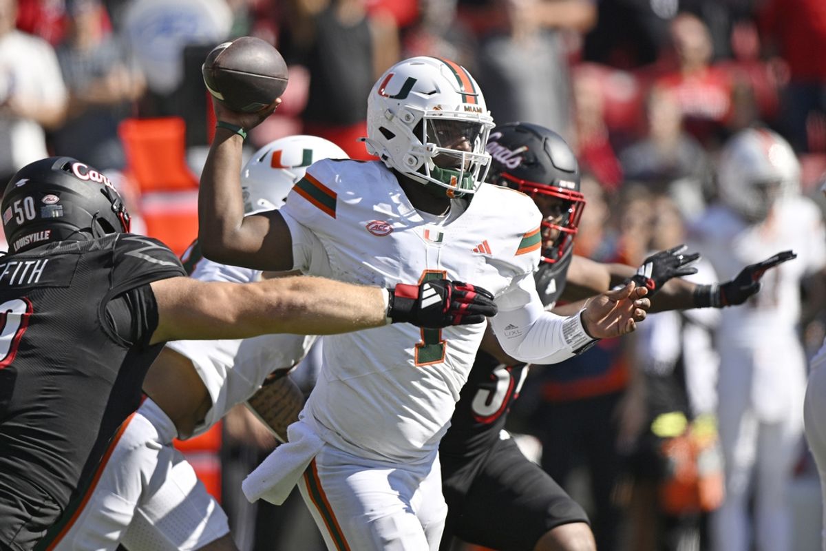 Oct 19, 2024; Louisville, Kentucky, USA; Miami Hurricanes quarterback Cam Ward (1) looks to pass under the pressure of Louisville Cardinals defensive lineman Thor Griffith (50) during the second half at L&N Federal Credit Union Stadium. Miami defeated Louisville 52-45. Mandatory Credit: Jamie Rhodes-Imagn Images
