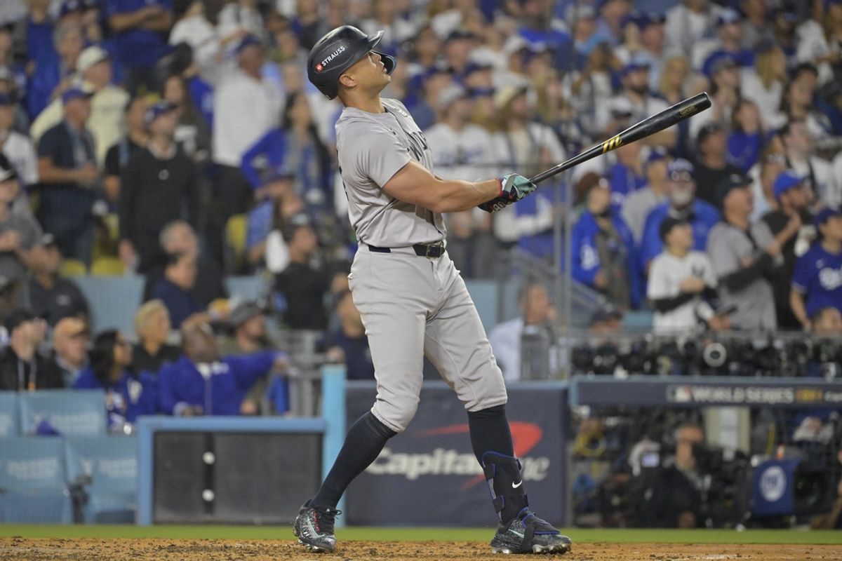 Oct 25, 2024; Los Angeles, California, USA; New York Yankees designated hitter Giancarlo Stanton (27) hits two-run home run in the sixth inning against the Los Angeles Dodgers during game one of the 2024 MLB World Series at Dodger Stadium. Mandatory Credit:  Jayne Kamin-Oncea-Imagn Images