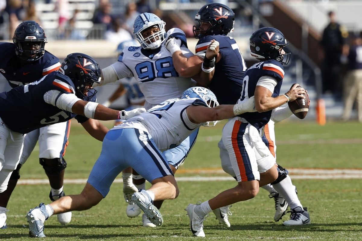 Oct 26, 2024; Charlottesville, Virginia, USA; Virginia Cavaliers quarterback Anthony Colandrea (10) is sacked by North Carolina Tar Heels defensive lineman Beau Atkinson (12) during the second half at Scott Stadium. Mandatory Credit: Geoff Burke-Imagn Images