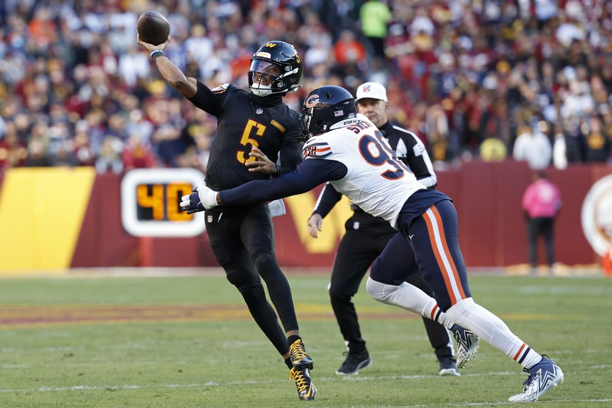 Oct 27, 2024; Landover, Maryland, USA; Washington Commanders quarterback Jayden Daniels (5) passes the ball as Chicago Bears defensive end Montez Sweat (98) chases during the first quarter at Northwest Stadium. Mandatory Credit: Geoff Burke-Imagn Images
