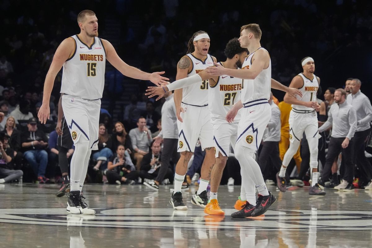 Oct 29, 2024; Brooklyn, New York, USA; Denver Nuggets center Nikola Jokic (15), point guard Jamal Murray (27) and guard Christian Braun (0) celebrate a play on the court against the Brooklyn Nets during overtime at Barclays Center. Mandatory Credit: Gregory Fisher-Imagn Images