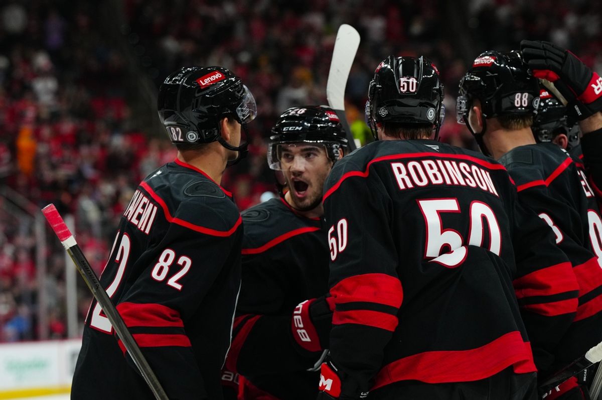 Oct 31, 2024; Raleigh, North Carolina, USA;  Carolina Hurricanes center Jesperi Kotkaniemi (82) is congratulated after his goal by defenseman Sean Walker (26) left wing Eric Robinson (50) and center Martin Necas (88) against the Boston Bruins during the third period at Lenovo Center. Mandatory Credit: James Guillory-Imagn Images