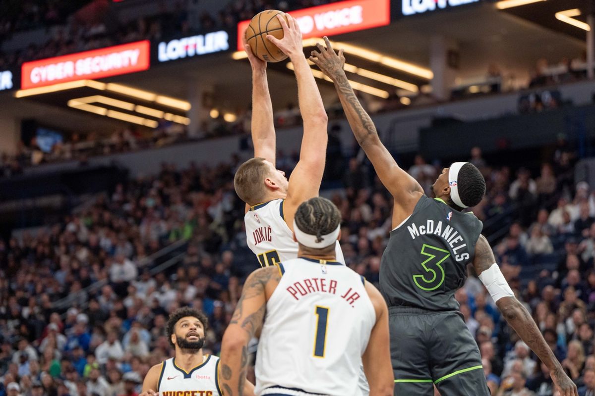 Nov 1, 2024; Minneapolis, Minnesota, USA; Denver Nuggets center Nikola Jokic (15) rebounds over Minnesota Timberwolves forward Jaden McDaniels (3) in the second quarter at Target Center. Mandatory Credit: Matt Blewett-Imagn Images