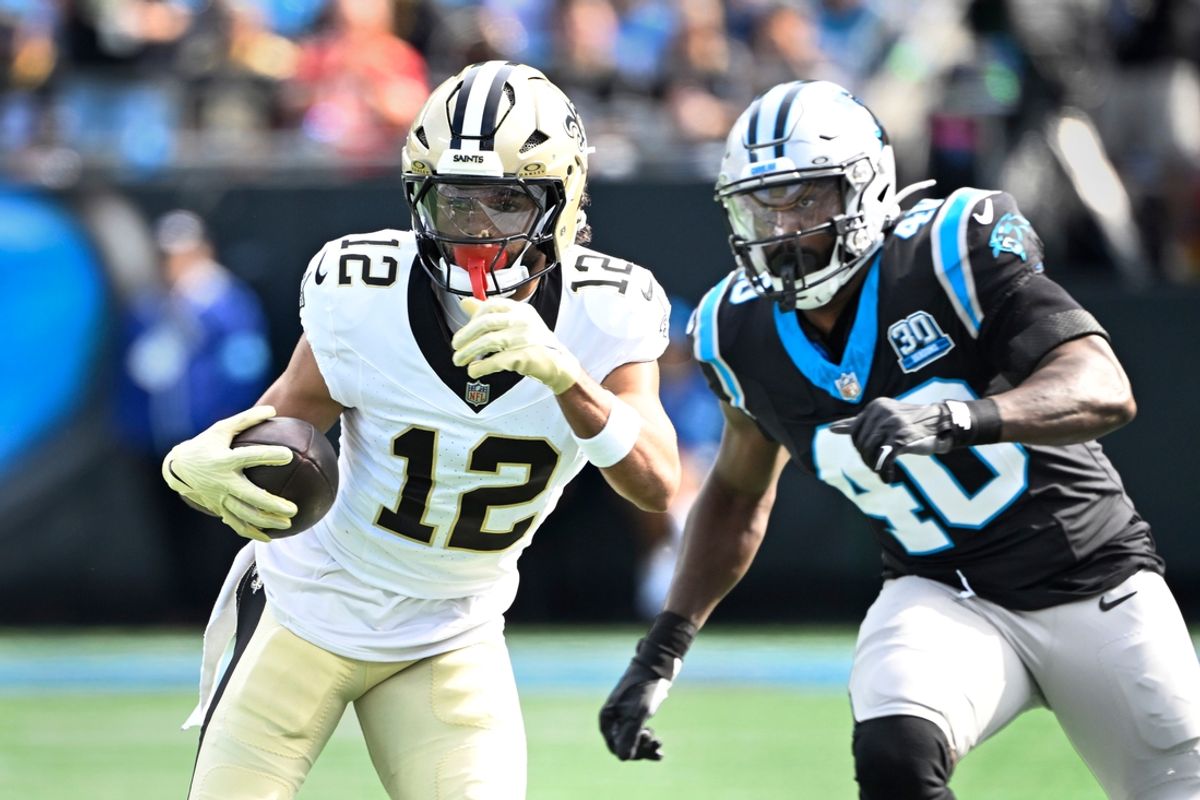 Nov 3, 2024; Charlotte, North Carolina, USA; New Orleans Saints wide receiver Chris Olave (12) with the ball as Carolina Panthers linebacker Charles Harris (40) defends in the first quarter at Bank of America Stadium. Mandatory Credit: Bob Donnan-Imagn Images