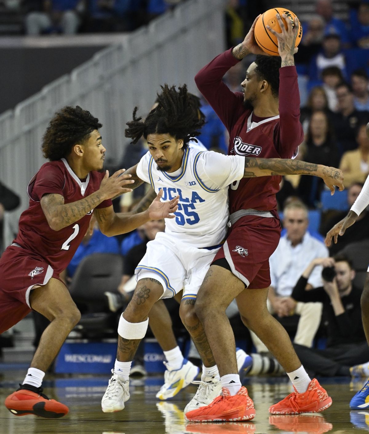 Nov 4, 2024; Los Angeles, California, USA; UCLA Bruins guard Skyy Clark (55) cuts between Rider Broncs guard Ruben Rodriguez (2) and forward Tank Byard (8) Pavilion during the first half at Pauley presented by Wescom. Mandatory Credit: Robert Hanashiro-Imagn Images